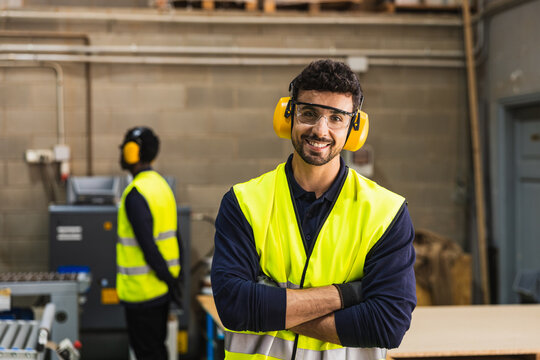 Confident worker smiling in lumberyard with safety gear
