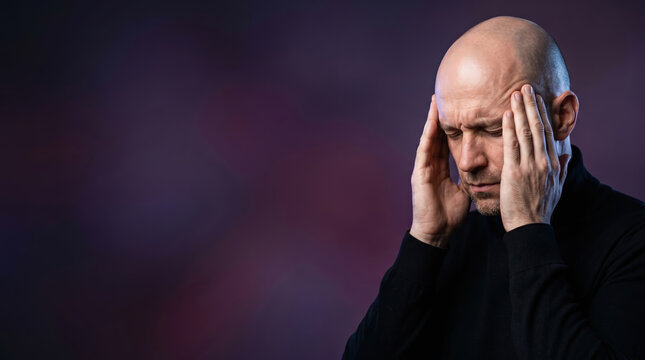Bald man praying with head in hand. Devout male character deep in silent meditation or spiritual concentration. Religious reflection and mental stress relief concept for spiritual health.