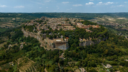 Obraz premium Aerial panoramic view of the historic town of Orvieto perched atop its volcanic tuff cliff, in the province of Terni, Umbria, Italy, with the Rocca Albornoz gardens visible on the clifftop edge.