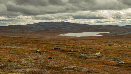 Enontekio, Finland - 31.08.2026: Vast arctic tundra landscape with a calm lake under dramatic overcast clouds and rolling treeless hills © Andrei