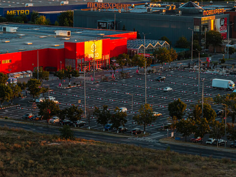 Bucharest, Romania Elevated morning view of Baneasa shopping area featuring Brico and Mobexpert retail stores with vast parking lot at sunrise.