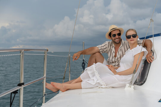 Happy couple relaxing on a sailboat at sea