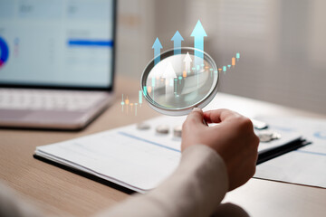 Fototapeta na wymiar Finance business investment and stock market growth. Woman hand holding magnifying glass analyzing upward arrow and candlestick trading chart.