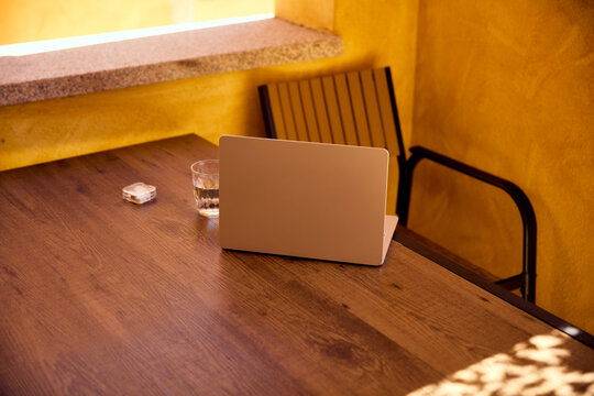 Laptop on wooden table on a sunny outdoor terrace workspace