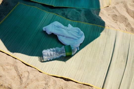 Water Bottle and White Towel on Beach Mat on Sand