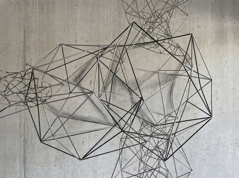 Abstract geometric wireframe sculpture with complex interconnected metal lines and shapes.