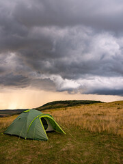 Camping Tents Under Dramatic Storm Clouds in Open Wilderness Landscape © Dan Badiu
