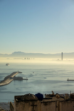 Misty morning view over Algiers harbor with breakwater lighthouse and cargo ship, North Africa, Algiers, Algeria