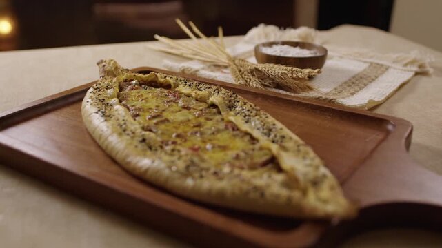 Freshly baked Turkish pide, a traditional flatbread with cheese and meat on a wooden platter