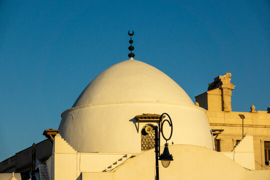 White dome and crescent finial of a historic mosque beside the old Chamber of Commerce building, North Africa, Algiers, Algeria