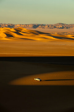 Aerial view of a pickup truck driving among sand dunes, North Africa, Erg Admer, Algeria