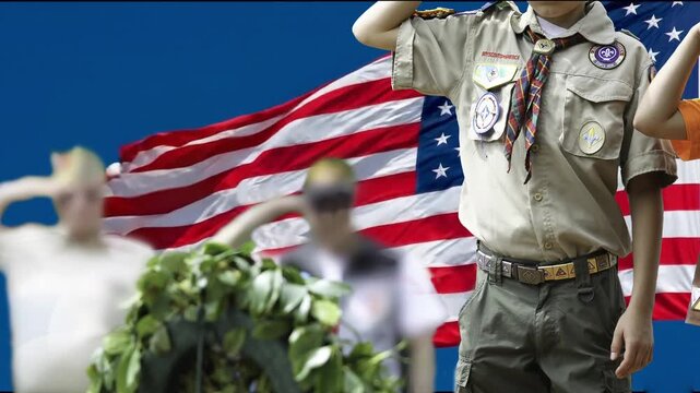 Veterans and scouts&rsquo; salute before a wreath, with the American flag waving in the wind in the background.