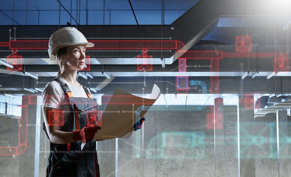 HVAC engineering. Female engineer inspects ventilation system drawings while verifying air duct installation and mechanical building services during construction.