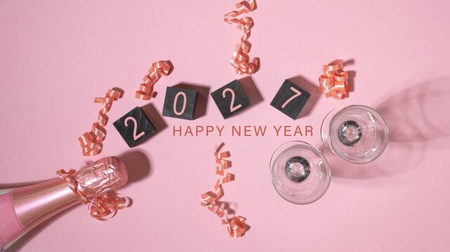happy new year 2027 Silvester New Year's eve party celebration greeting card - Pink champagne bottle, sparkling wine, champagne glasses, isolated on pink table background, top view