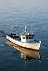 Fototapeta premium Sustainable fishing and maritime industry, small commercial boat moving through calm blue water for coastal trade and local seafood supply chain