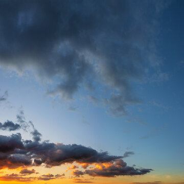 bright rays of setting sun among clouds in blue sky