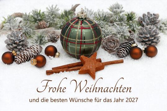 Weihnachtskarte:  Christbaumkugeln, Tannenzapfen, und beschneite Tannenzweige. Im Schnee steht der Schriftzug &bdquo;Frohe Weihnachten und ein gutes neues Jahr 2027&ldquo;.