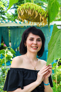 Portrait an adult woman in off-the-shoulder clothing, on a sun-drenched alley among blooming yellow sunflowers and tall palm trees.