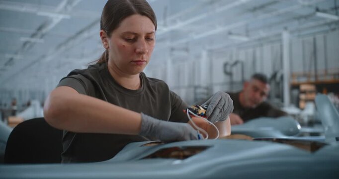 Focused Professional Technician Carefully Mounts Circuit Boards Inside Fixed Wing UAV, Demonstrating Precise Electronic Integration and Aircraft Assembly in Modern Aerospace Production Facility.