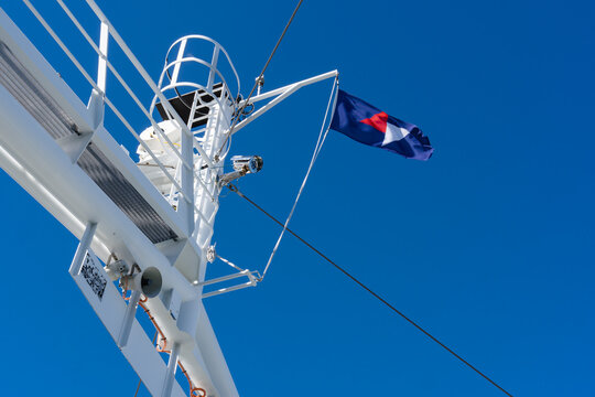 August 17, 2026, Fodnes, Norway - Blue flag with red and white star flying from a ship's mast against a clear blue sky