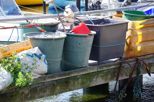 Eimer stehen auf einem Bootssteg im Hafen an der Ostsee in Strande, Schleswig-Holstein