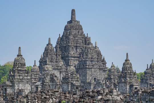 Ancient Sewu Buddhist temple stone ruins with ornate stupas under a clear blue sky in Klaten, Central Java, Indonesia on a bright sunny day.