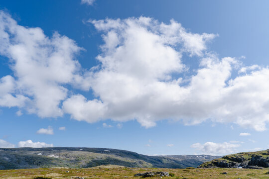 Vast Norwegian mountain plateau with rolling hills under a bright blue sky