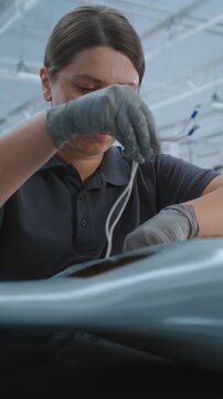 Skilled Female Engineer Integrates Electronic Boards In Interior of Fixed Wing UAV, Highlighting Advanced Aircraft Systems Installation and Precision Assembly in Bright Modern Factory. Vertical Shot.
