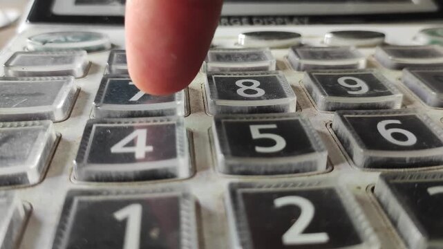 Close up of a finger pressing buttons on a calculator keypad for financial accounting and business calculations