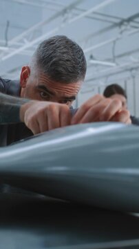 Male Technician Manually Fits Hardware and Electronic Components Inside Unmanned Aircraft Body During Precision Assembly at Large Modern Aerospace Factory. Concept of Manual Assembly. Vertical Shot.