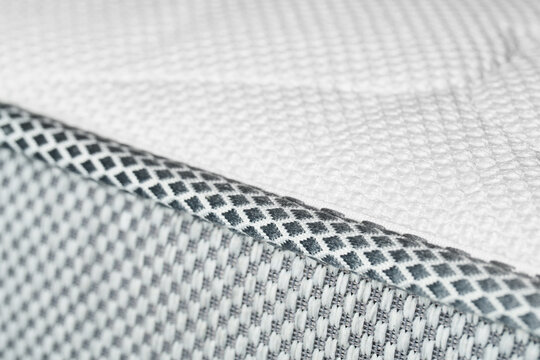 The macrotexture of the white edging and the fabric of the orthopedic mattress.