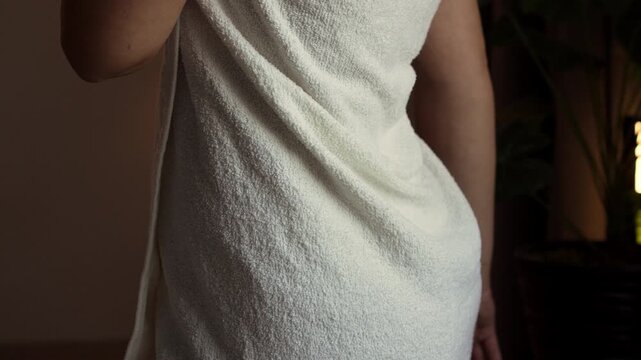 Rear view of woman wrapped in towel holds condom package in hand. contraceptive use for pregnancy prevention.