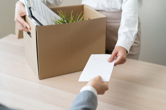 Close up of employee handing resignation letter to manager with cardboard box.
