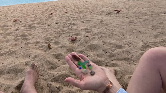 Woman Holding Colorful Beach Stones Before Revealing a Beautiful Tropical Beach in Ilhabela, Brazil