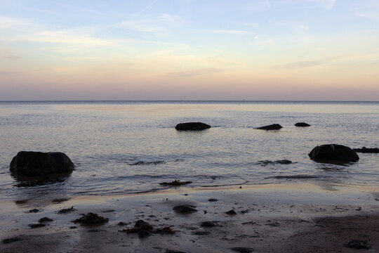 Atmospheric coastal landscape with stones on the beach at twilight