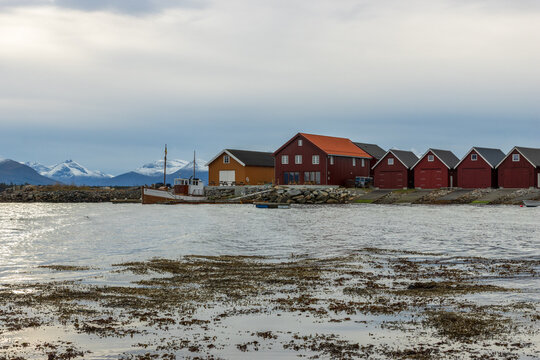 Scenic harbor in Molde, Norway with traditional wooden huts and snow-capped peaks of Tresfjord