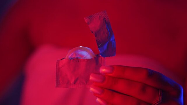 Healthcare and medicine concept. woman wrapped in towel open condom package. contraceptive for pregnancy prevention