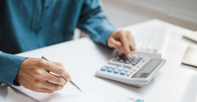 He writes carefully beside a device as payroll review guides calculation for human work and human resources, while payroll notes support review through calculation of human tasks and human resources.