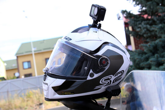Vinnytsia, Ukraine; September 05, 2026. White LS2 full-face motorcycle helmet with black and gray graphics, glossy shell, clear visor, padded interior, compact black action camera DJI mounted on top. 