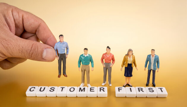 Hand selecting a miniature figure above letter blocks spelling customer first
