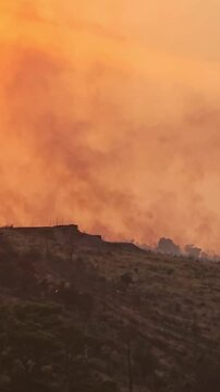 Wildfire smoke over a dry hillside at sunset in Sutomore