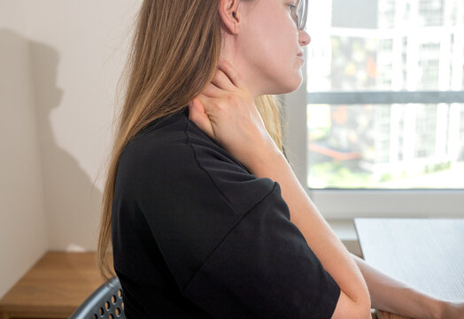 Businesswoman touching aching neck during stressful computer work at office desk. Overworked female freelancer suffering from severe cervical myositis and professional burnout. Office syndrome health