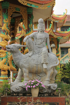 Stone Guanyin statue riding a water buffalo, traditional Asian goddess of mercy sculpture with ornamental background