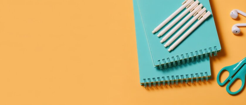 Stationery items and notebooks on orange background for back to school or office work.