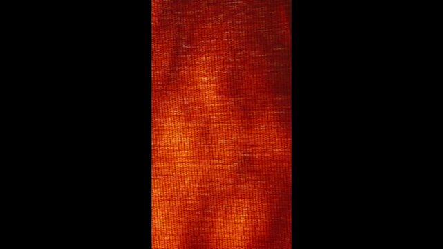 dark shadows dance against the backdrop of a thick orange curtain