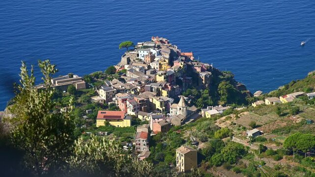 Mediterranean village nestled on hillside overlooking deep blue sea. Corniglia, Italy