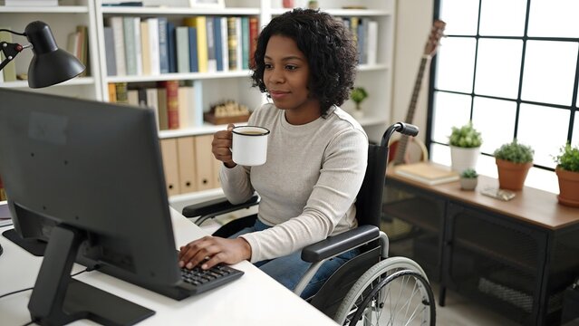 African American woman in a wheelchair using a computer while holding a coffee cup