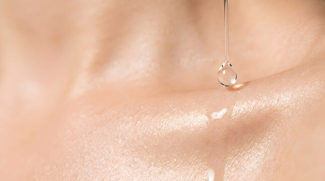 Macro shot of clear serum drop falling on woman skin. Hydrating cosmetic oil and essence skincare application