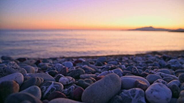 Pebble beach with gentle waves rolling toward shore at sunset