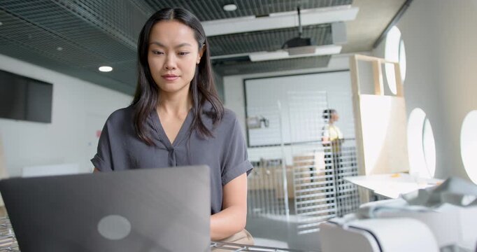 Young Adult Businesswoman Focusing on Laptop in Modern Open plan Workspace